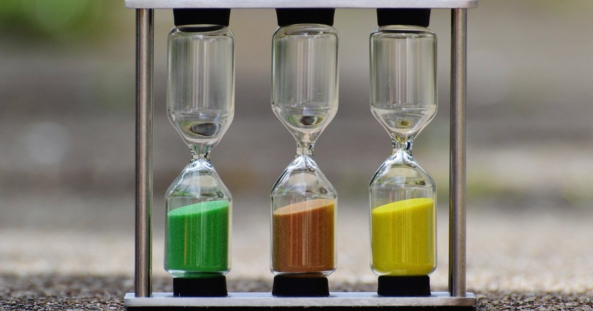 Three hourglasses side by side, each with a different colour of sand